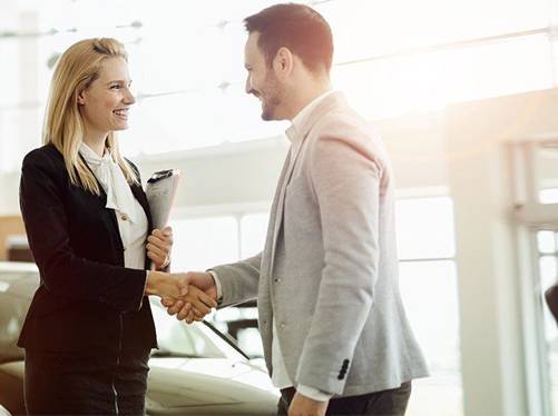 Ejecutiva y cliente estrechando la mano en una agencia de autos